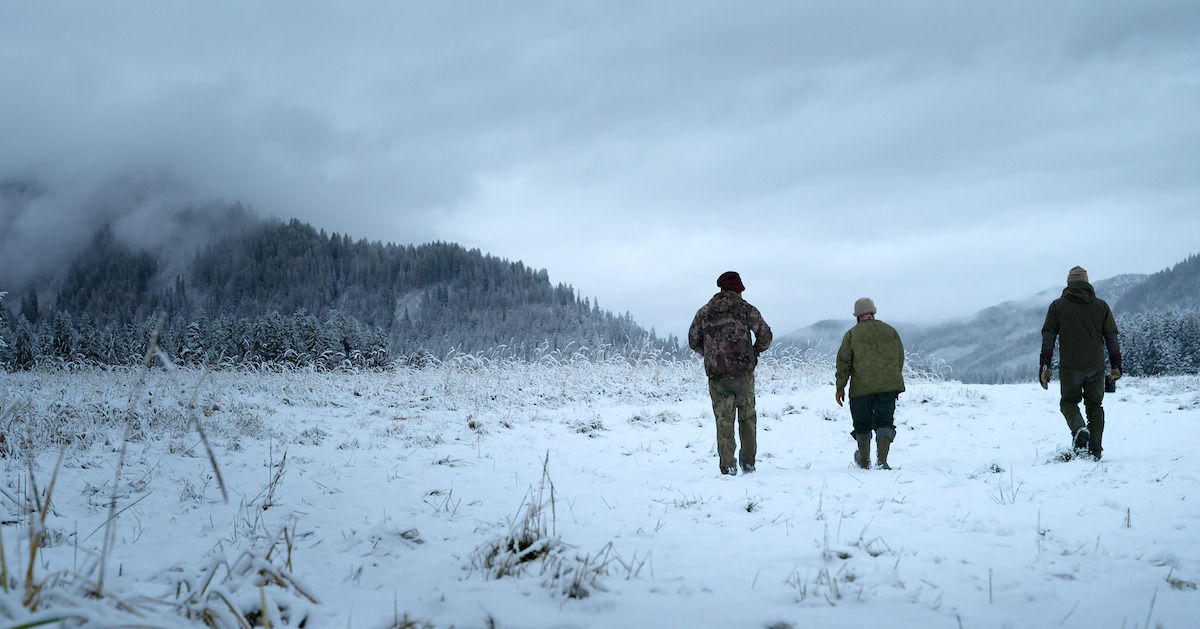 three people walking on a snowy field