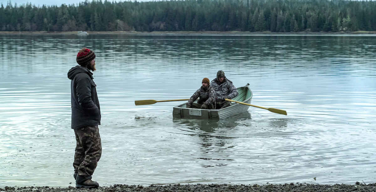 Drew Haas and Drake Vliem on a boat as Sammy Norris looks on from the shore.