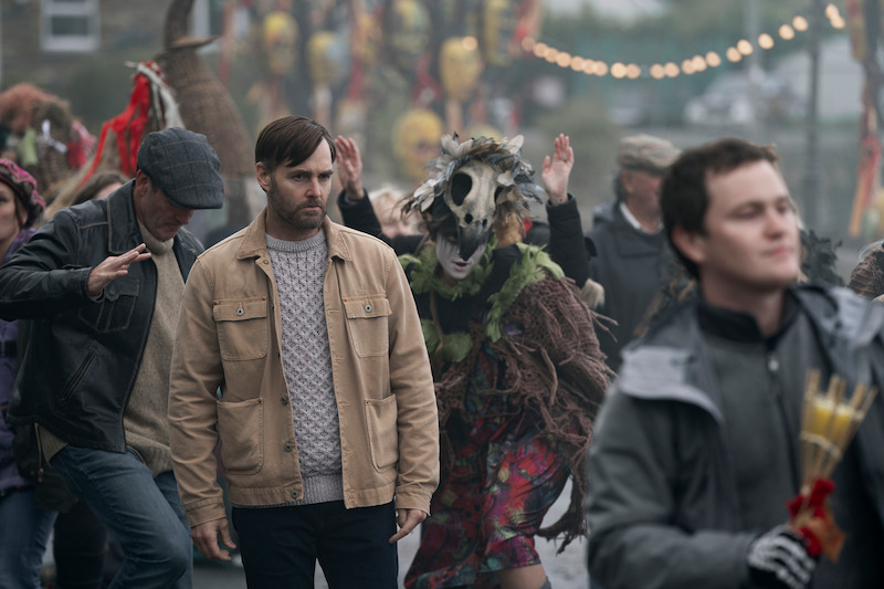 Will Forte as Gilbert Power walks through a crowd at a festival in 'Bodkin'
