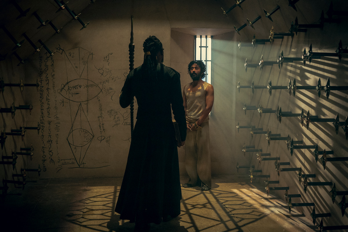 Two characters standing in a dungeon with spikes on the wall