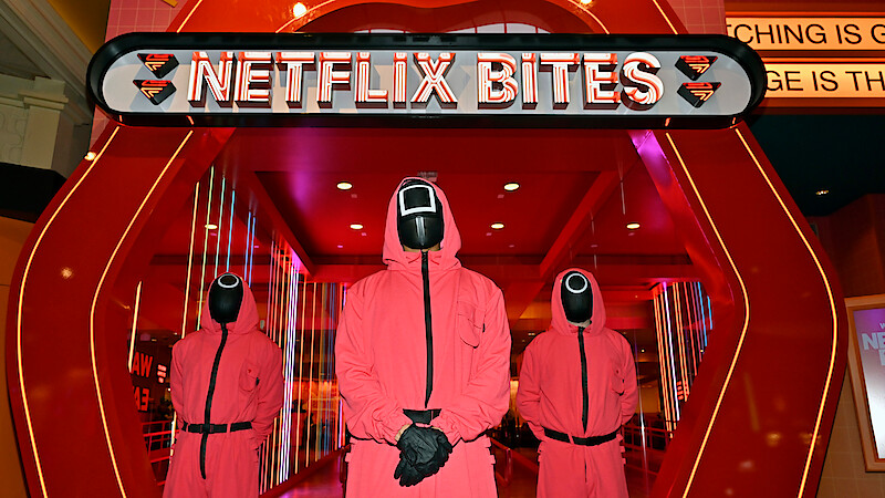 Three masked men from 'Squid Game' stand in front of the entrance to Netflix Bites Las Vegas at the MGM Grand