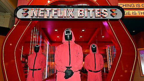 Three masked men from 'Squid Game' stand in front of the entrance to Netflix Bites Las Vegas at the MGM Grand